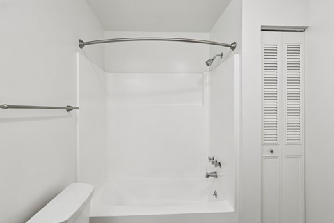 A white bathroom with a tub and a towel rack.