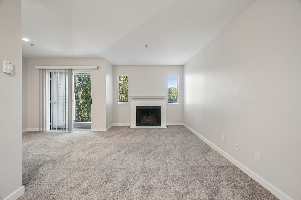 A spacious living room with a fireplace and a carpeted floor.