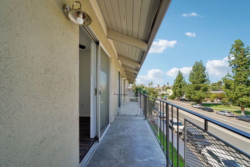 A balcony with a metal railing and a concrete floor.