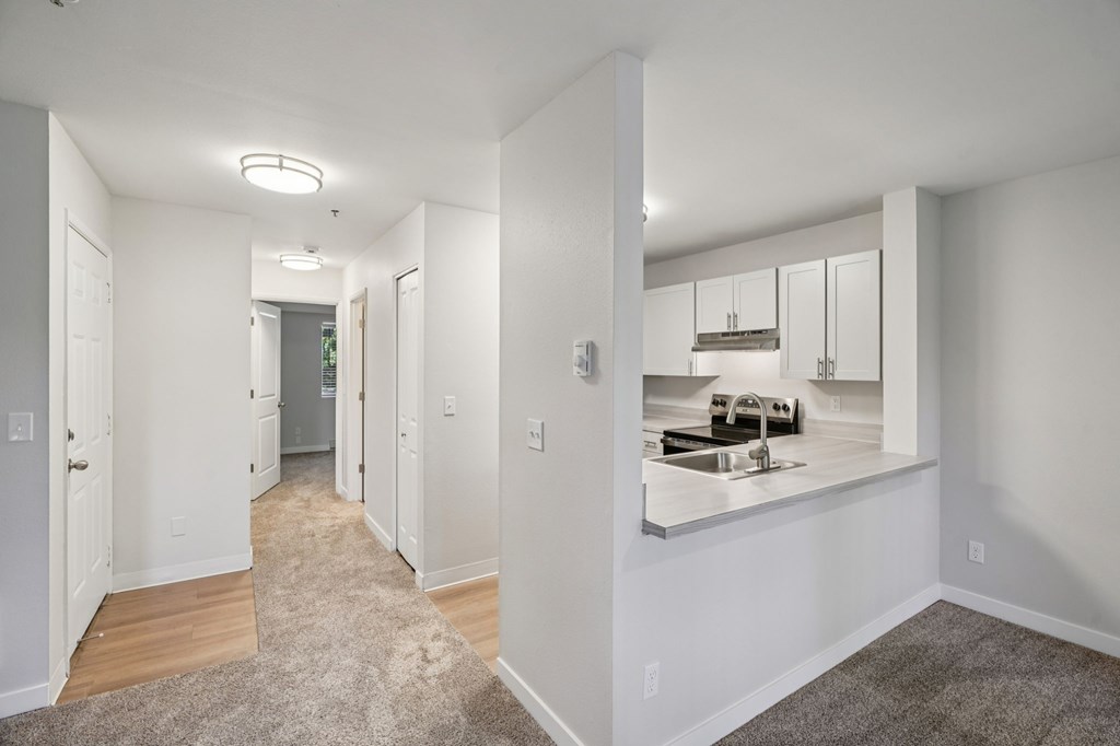 A hallway with a kitchen visible in the mirror.