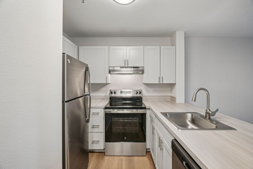 A kitchen with a refrigerator, stove, oven, and sink.