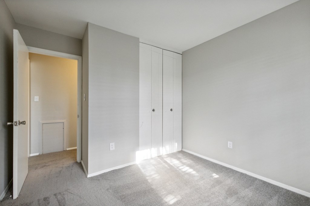 an empty bedroom with white cabinets and a door to a closet at Briarwood Apartments, Dumfries, Virginia