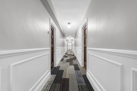 A long hallway with a striped carpet and white walls at Pleasant Oak Apartments, Illinois