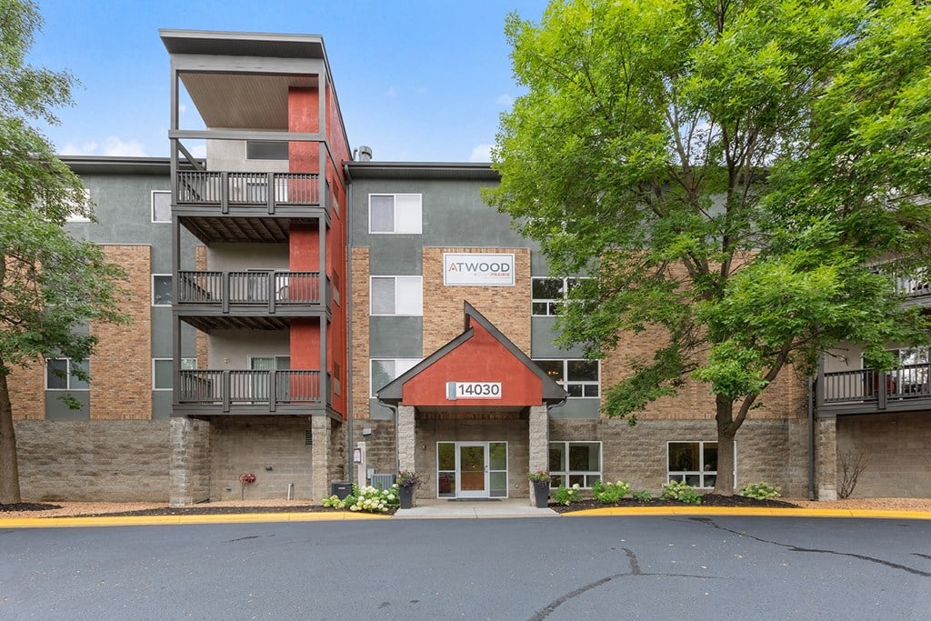 an apartment building with brick and stone exterior and trees
