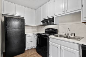 an empty kitchen with white cabinets and black appliances