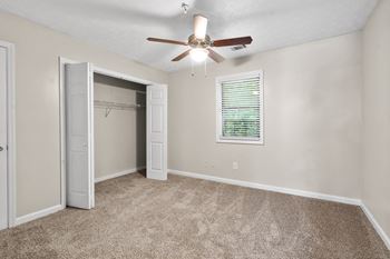 an empty room with a ceiling fan and a closet
