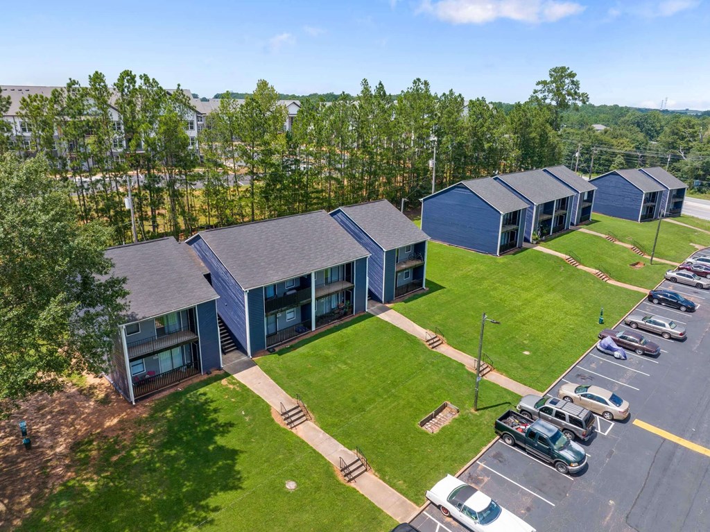 a row of blue houses with a grassy area and trees in the background at Alcovy Terrace, Georgia, 30014
