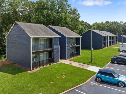 a row of blue buildings with gray roofs and a blue car parked in a parking lot at Alcovy Terrace, Georgia, 30014