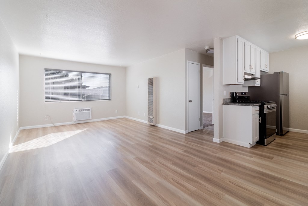 the living room and kitchen of an apartment with a hard wood floor at Alturas Paso Robles Apartment Homes, Paso Robles, CA