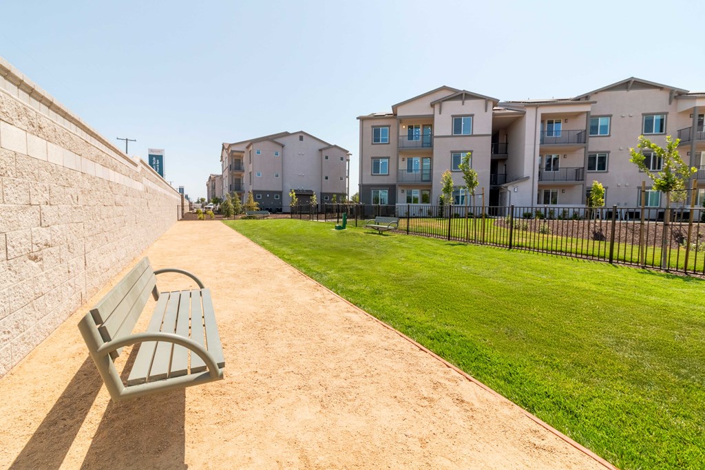 A park with a bench and apartment buildings in the background.