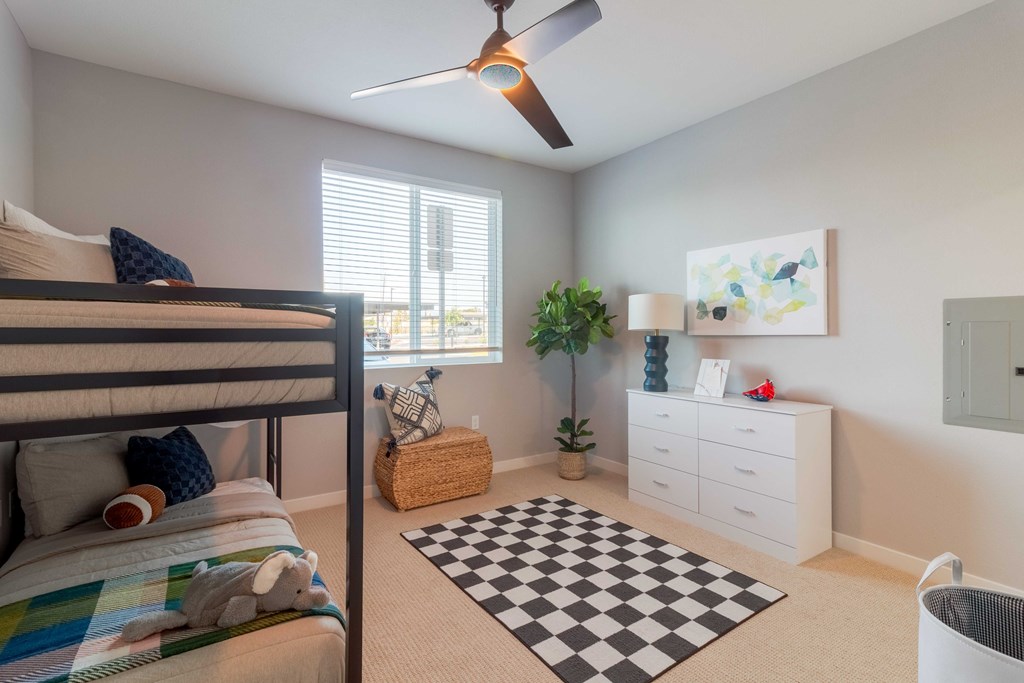 A bedroom with a bed, a ceiling fan, a dresser, and a rug.