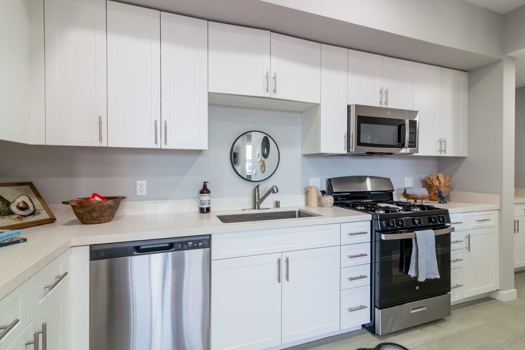 A modern kitchen with white cabinets and stainless steel appliances.