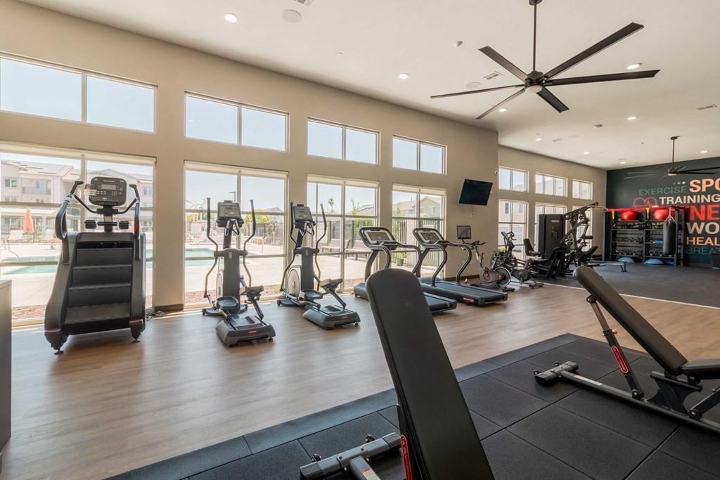 A gym with a variety of exercise equipment including treadmills, stationary bikes, and weight machines.
