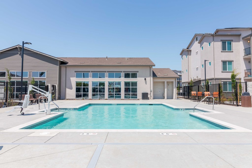A large swimming pool in front of a building with a clear blue sky above.
