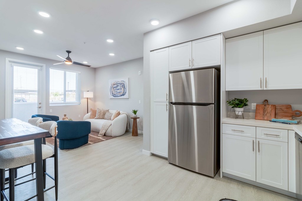 A modern kitchen with a stainless steel refrigerator and white cabinets.