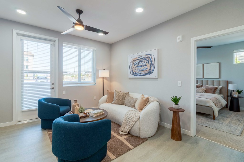 A living room with a blue chair, a white couch, and a ceiling fan.
