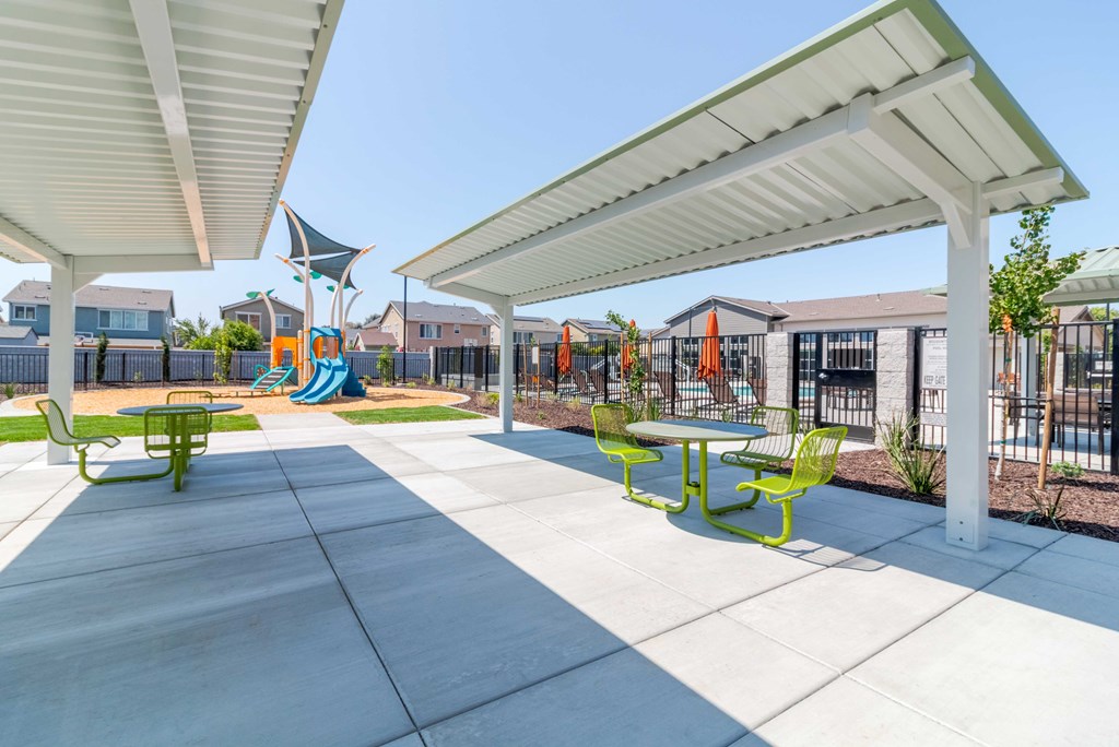 A courtyard sitting area with shade and a playground in the background