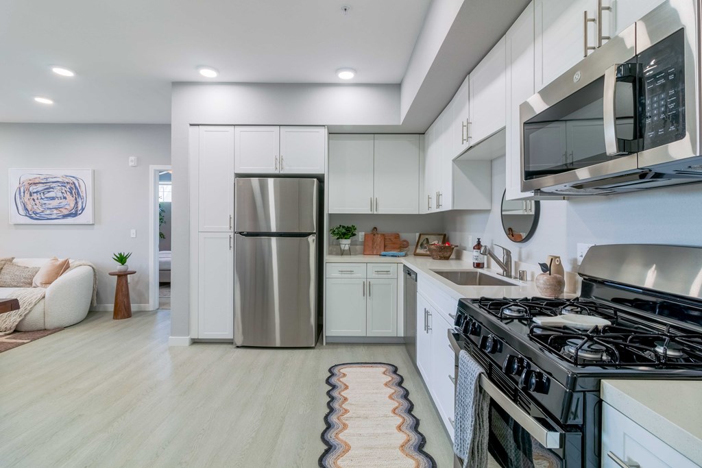 A modern kitchen with a stainless steel refrigerator and a black microwave above the stove.