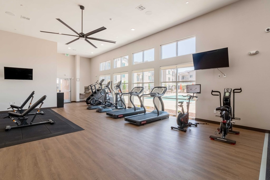 A spacious gym with a variety of exercise equipment and a ceiling fan.