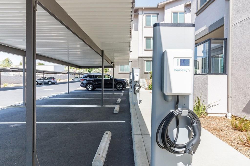 A charging station for electric vehicles is located under a covered parking area.