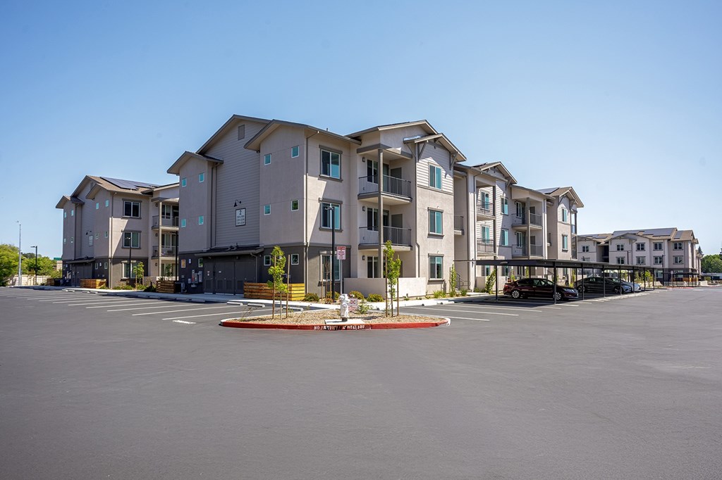 A large apartment building with a parking lot in front of it.