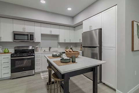 A modern kitchen with a table and chairs in the middle.