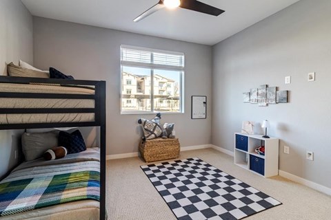 A bedroom with a bunk bed and a window overlooking a building.