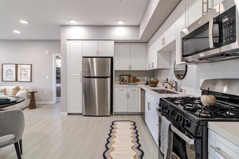 A modern kitchen with a stainless steel refrigerator and a black stove top.