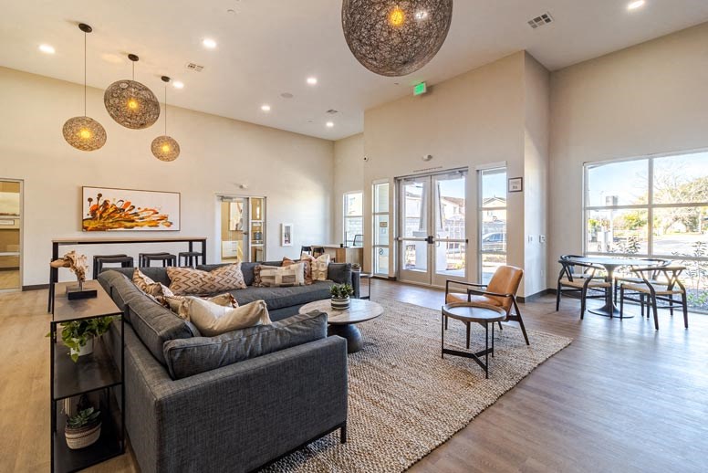 A spacious living room with a grey sofa and a large window.