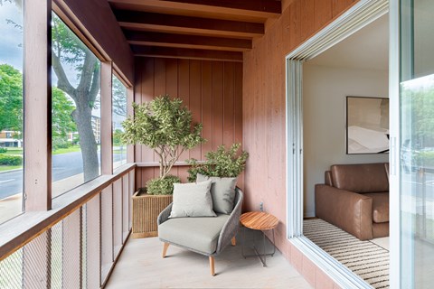 A balcony with a chair and a small tree.