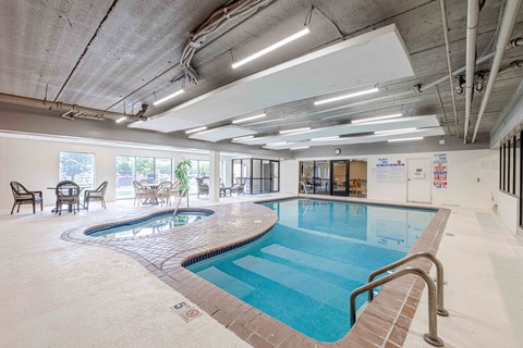 A large indoor swimming pool with a mosaic tile edge and a metal ladder.