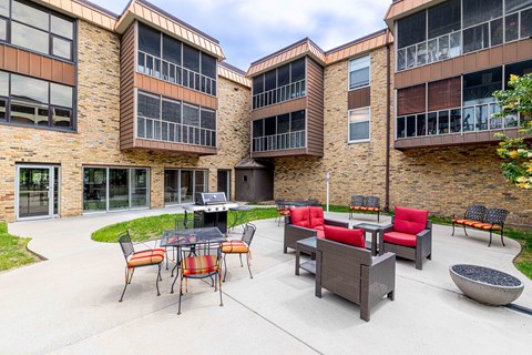 A patio area with a table and chairs in front of a brick building.