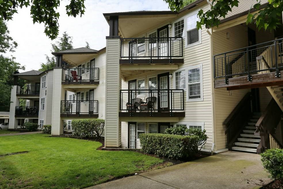 an apartment building with balconies and a grass yard at Sundial Apartments, Wilsonville