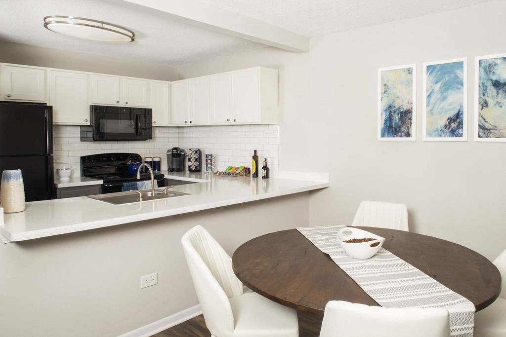 a dining area with a table and chairs and a kitchen in the background at Fifteen 98 Naperville, Naperville