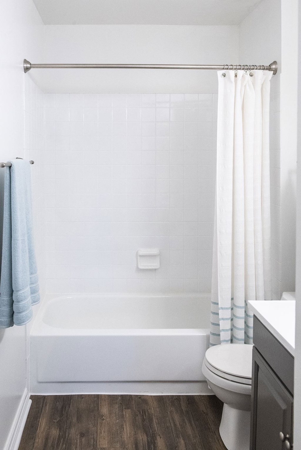 a bathroom with a white bathtub and a white toilet with a blue and white shower curtain  at Fifteen 98 Naperville, Naperville