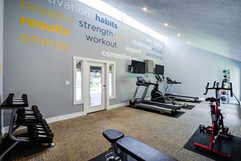 a gym with treadmills and other exercise equipment in a room with a wall