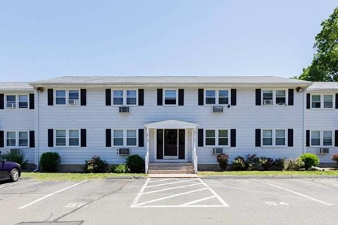 the front of a white building with a parking lot
