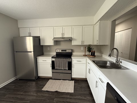 A kitchen with white cabinets and a stainless steel refrigerator.