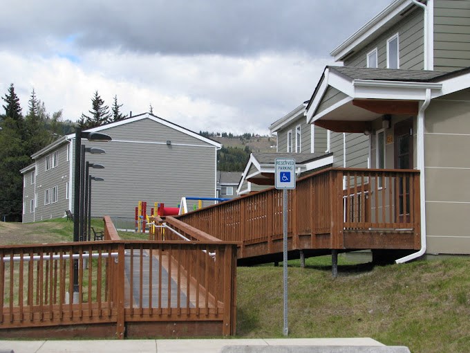 apartment home with a deck and a playground in front of it at Conifer Woods Apartments, Homer, 99603