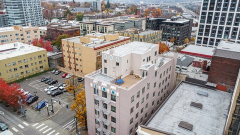 A cityscape with a mix of modern and older buildings, a parking lot, and trees with autumn foliage.