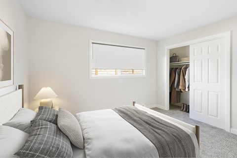A bedroom with a bed, pillows, a lamp, and a closet.