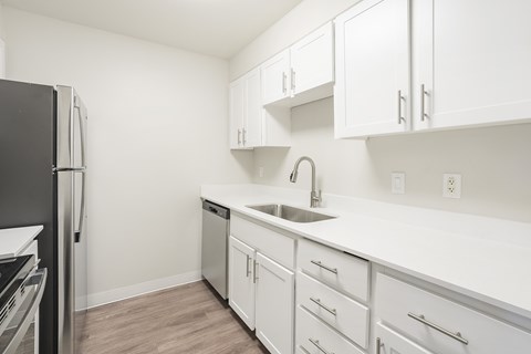 A kitchen with white cabinets and a black refrigerator.