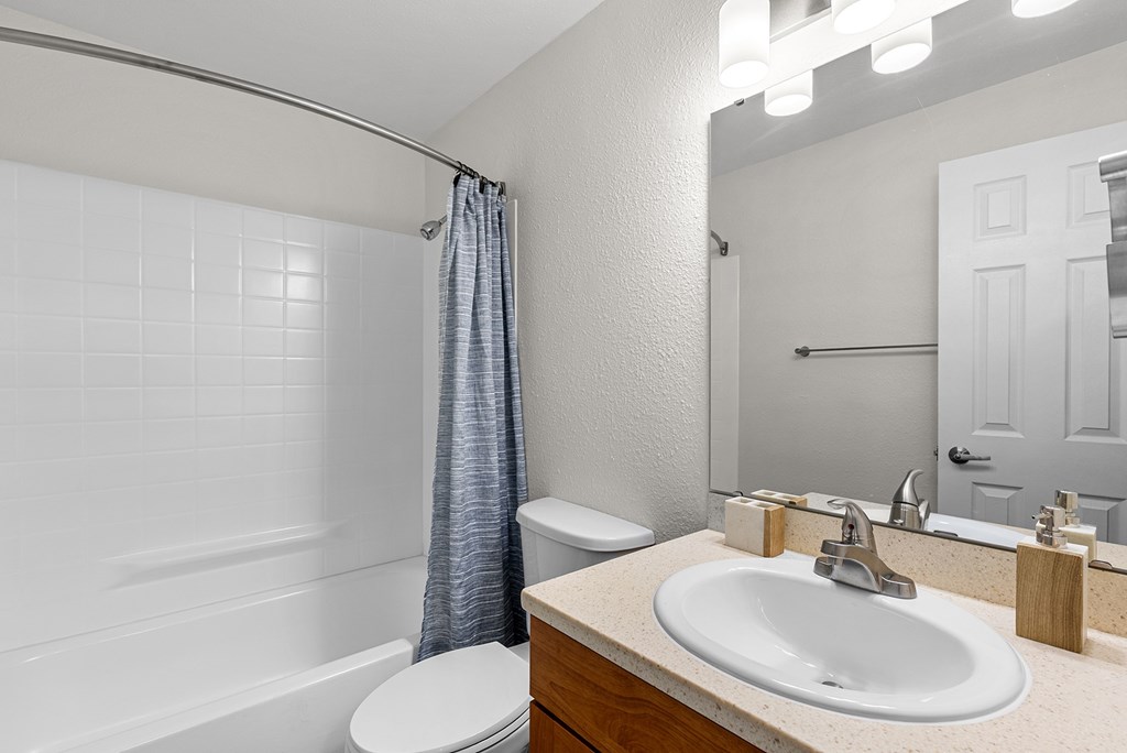 A white bathroom with a toilet, sink, and shower.
