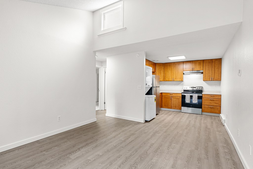 Living room with view of the kitchen with wooden cabinets and a white refrigerator.