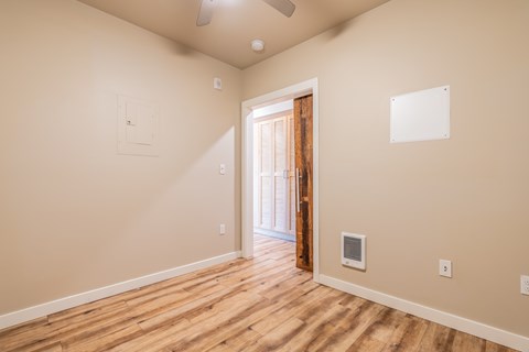 Empty room with rustic wood door accent and ceiling fan at Brooklyn Yard Apartments, Portland