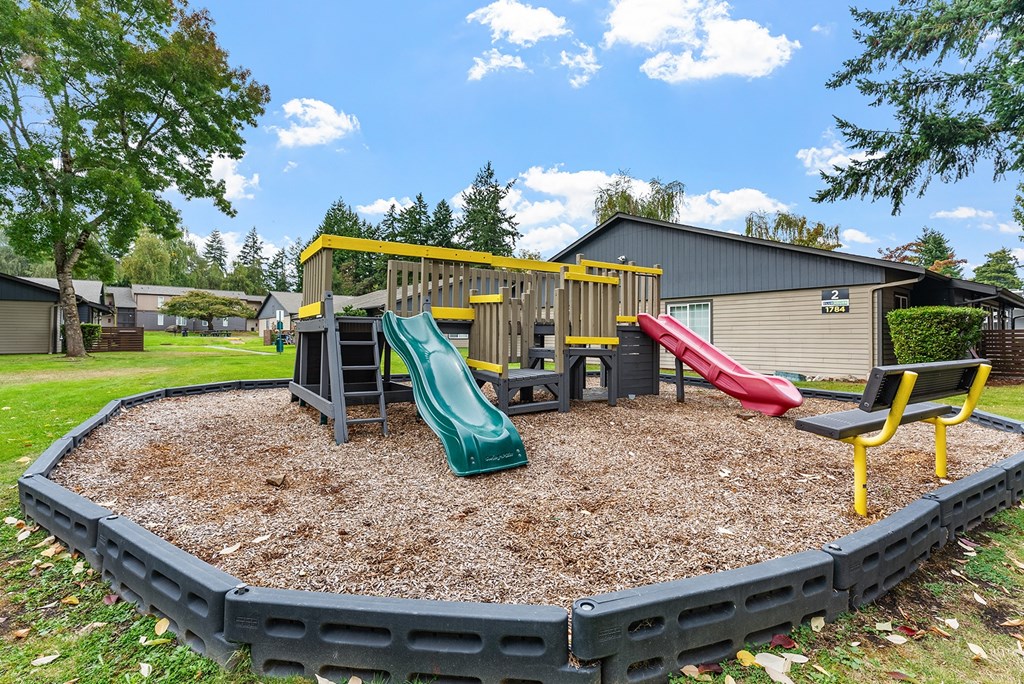 A playground with a green slide and a red slide.