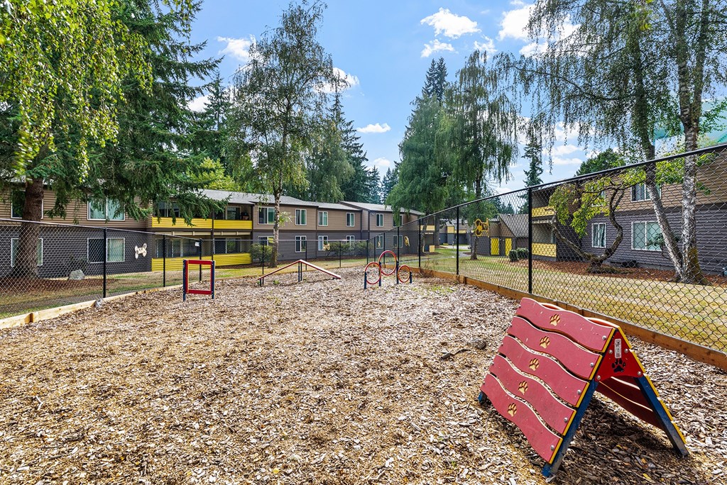 A playground with a red slide and a fence in the background.
