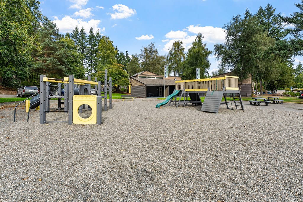 A playground with a yellow slide and a green slide.