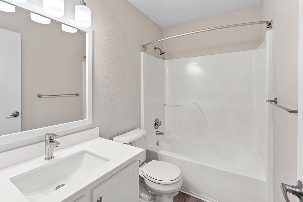 A white bathroom with a toilet, sink, and shower.