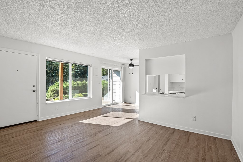 Large living room with wooden floors and a view of the kitchen